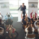 Confident speaker addressing a seated audience during a presentation, illustrating public speaking tips