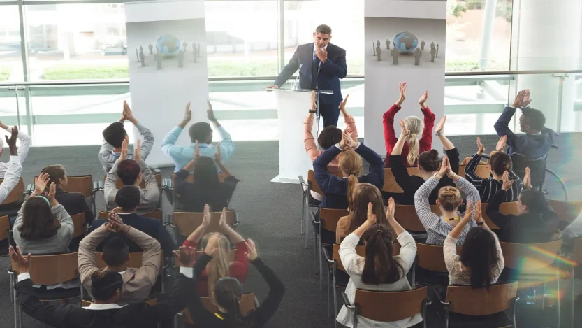 Confident speaker addressing a seated audience during a presentation, illustrating public speaking tips